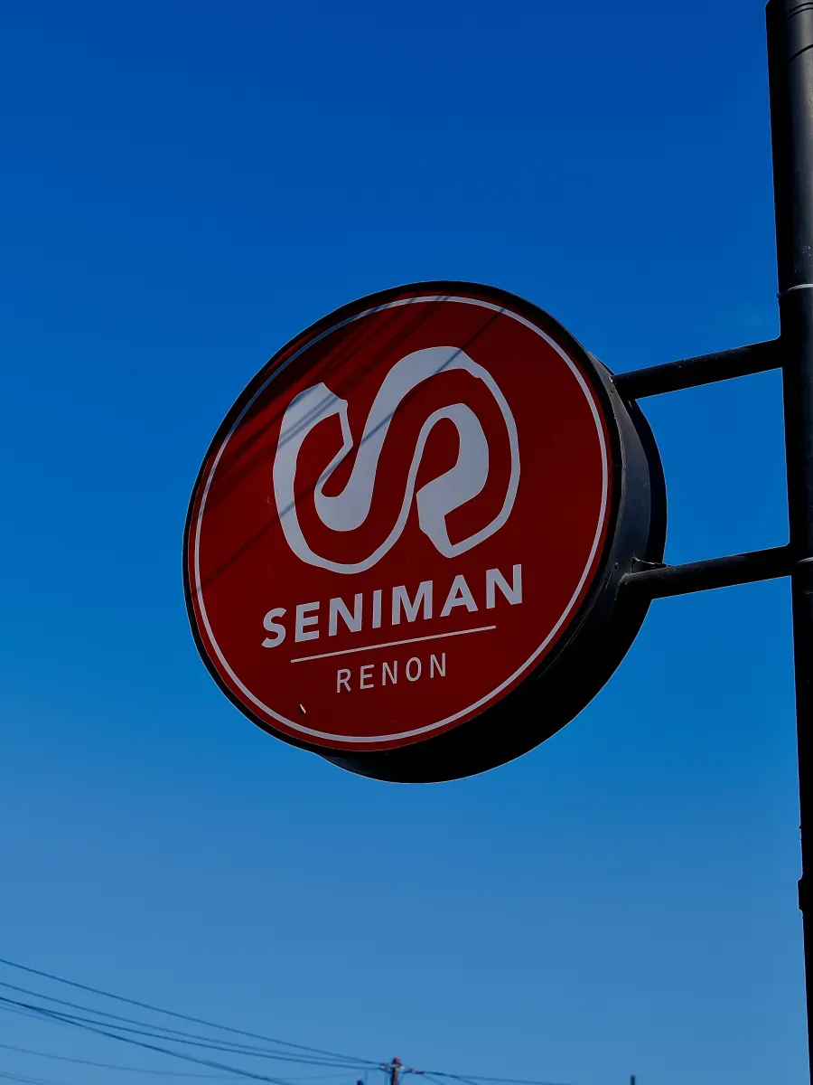 Seniman Coffee Renon sign against a clear blue sky