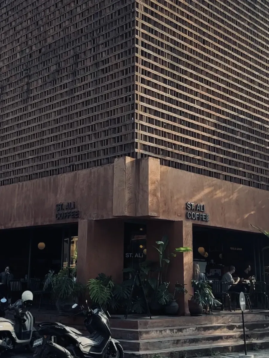 ST. ALi Coffee terracotta corner building with brick lattice facade and tropical plants at the entrance